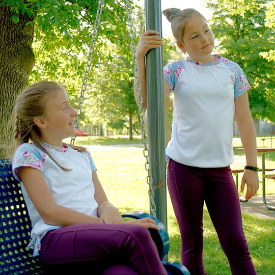 two women are sitting on a park bench 