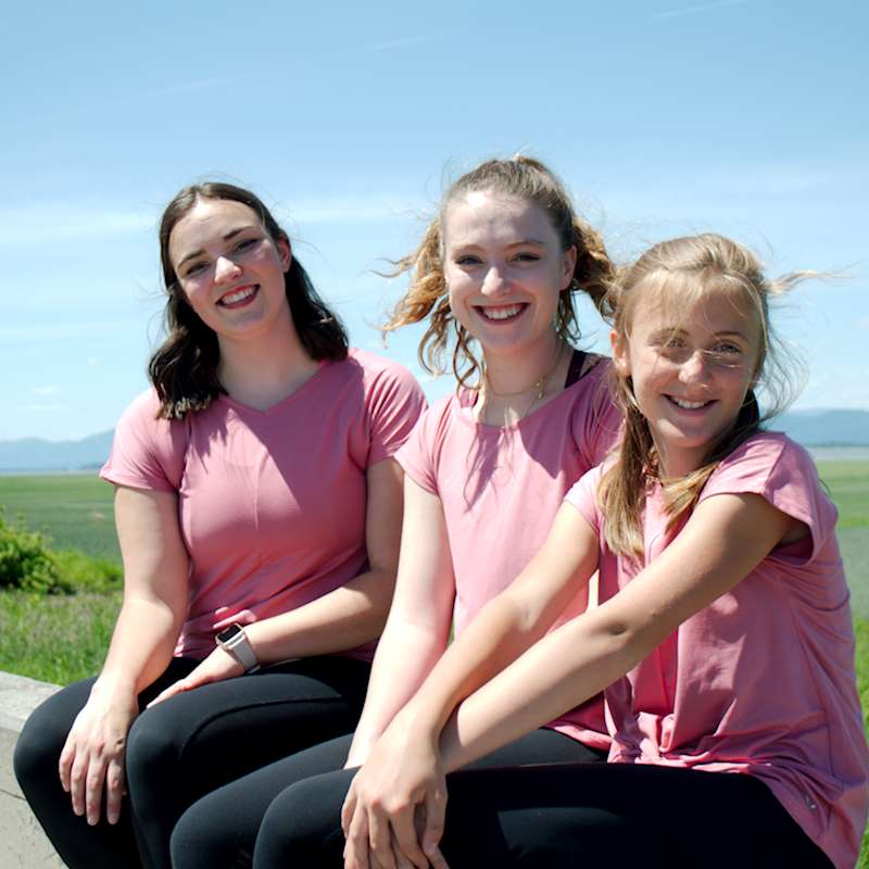 a group of women sitting on a park bench 