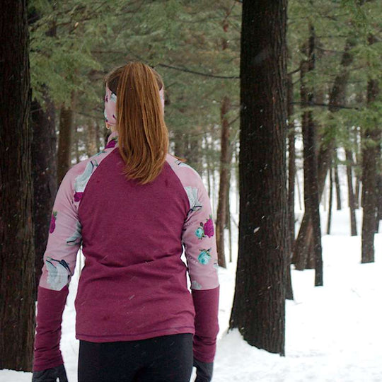 a woman standing in the snow next to a tree 